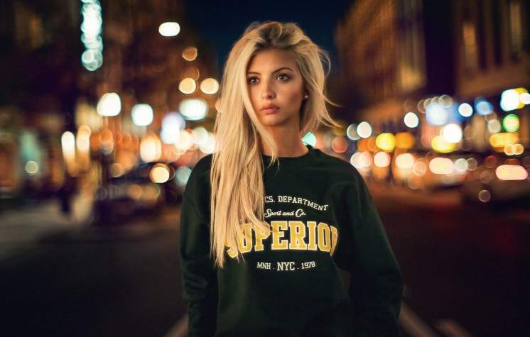 Красивая девушка в огнях вечернего городка на фото