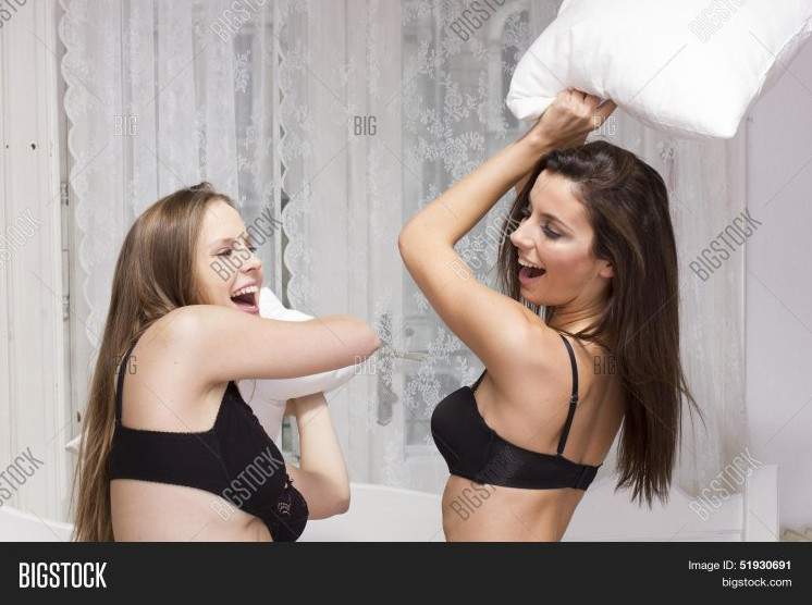 Очаровательные женщины дерутся подушечками на фото