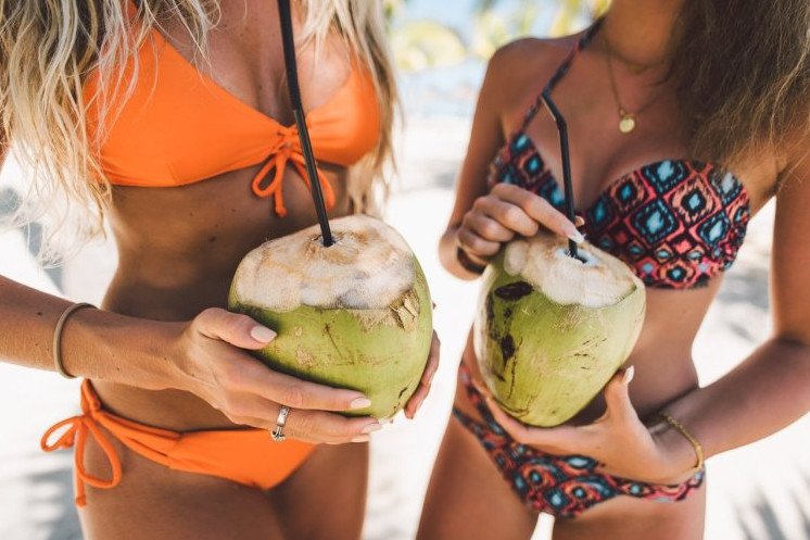 Красивая девушка на пляже с кокосом на фото