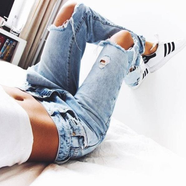 Красивая девушка в джинсах на кровати